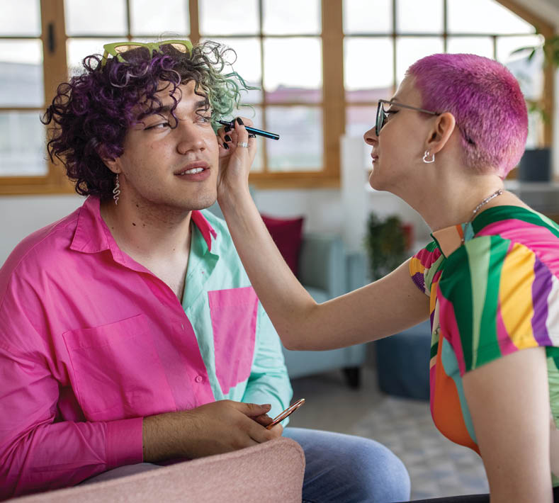 Caucasian homosexually oriented male and male friends, with half anf pink dyed hairs, doing makeup